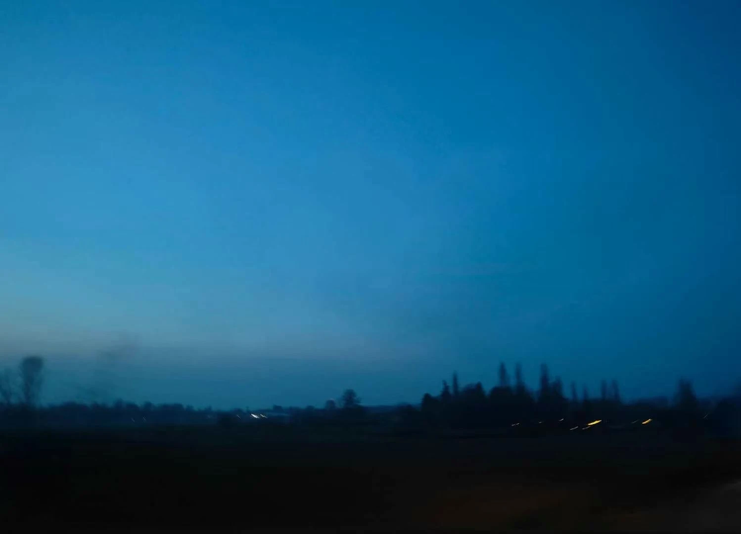 A blurred dark horizon beneath a deep blue evening sky