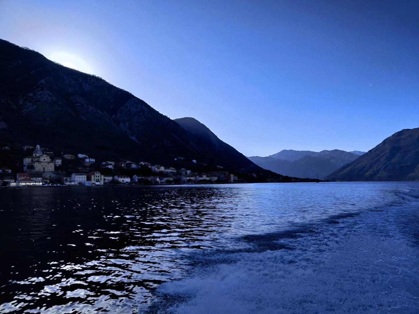 Blue mountain lake with a boat wake and waterside buildings