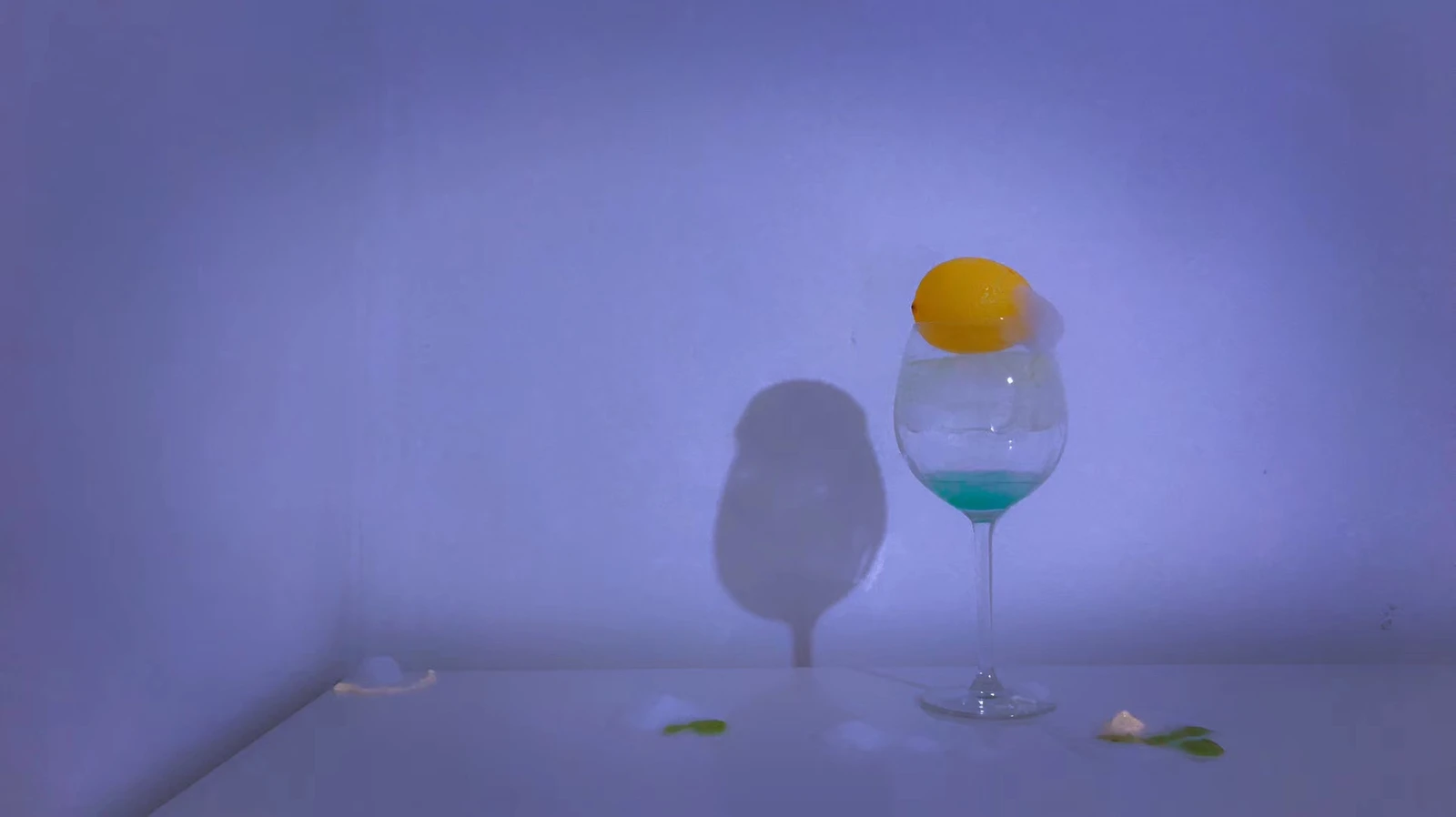 A citrus fruit balanced on a glass in violet light