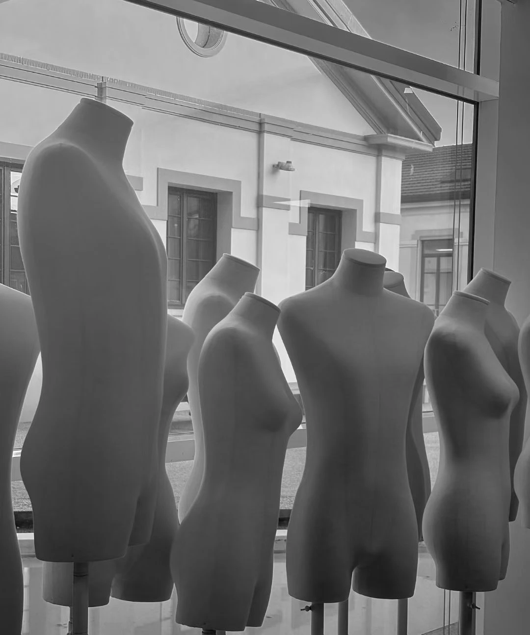 Black and white photograph of dress forms by a window